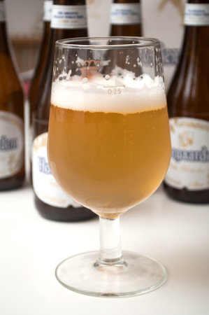 Mulhouse - France - 25 November 2019 - Closeup of the famous belgian Hoegaarden of white bier in glass on bottles backgroundのeditorial素材