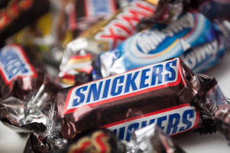Mulhouse - France - 26 November 2019 - Closeup of Snickers chocolate bar by Mars compagny in brown packaging on white backgroundのeditorial素材