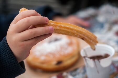 Closeup of churros in hand of kid at the christmas marketの写真素材