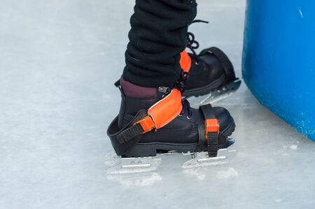 Closeup of feet of children with ice skates on an ice rink