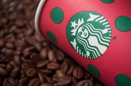 Mulhouse - france - 28 November 2019 - Closeup of merry christmas take away cup by Starbucks brand on coffee beans background, Starbucks is the famous chain of fast foodのeditorial素材