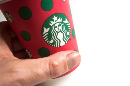 Mulhouse - france - 28 November 2019 - Closeup of merry christmas take away cup in hand from Starbucks brand on white background, Starbucks is the famous chain of fast foodのeditorial素材