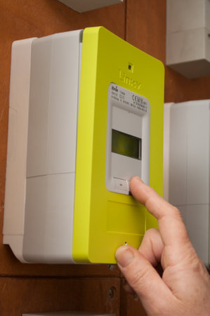 Mulhouse - France - 27 November 2019 - Closeup of hand of woman on New smart electric meter Linky from ERDF (Electricity Network Distribution France) in the entry of Buildingのeditorial素材