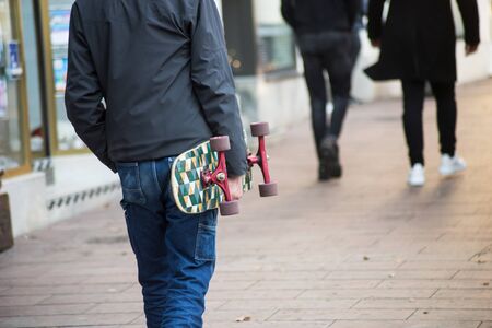 Closeup od young man walking in the strett with skateboard in hand の写真素材