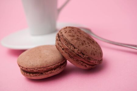 Closeup of french macarons and cup of coffee on pink background 