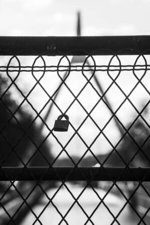closeup of love padlock on metallic fence on blurred landscape background in black and whiteの写真素材