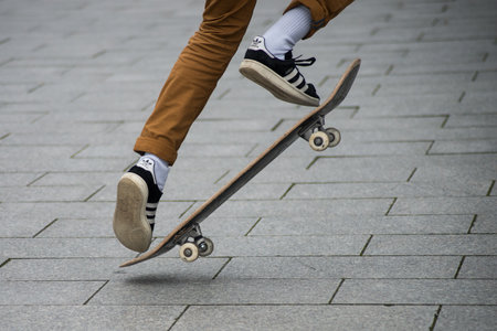 Mulhouse - France - 31 January 2020 - Closeup of skater legs wearing black sneakers by Adidas  jumping with skate board in the streetのeditorial素材