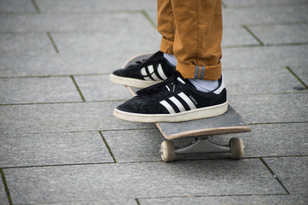 Mulhouse - France - 31 January 2020 - Closeup of skater legs wearing black sneakers by Adidas  standing on skate board in the streetのeditorial素材