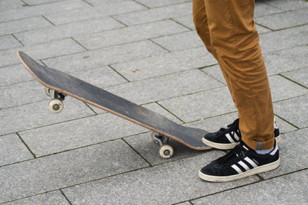 Mulhouse - France - 31 January 2020 - Closeup of skater legs wearing black sneakers by Adidas waiting with skate board in the streetのeditorial素材