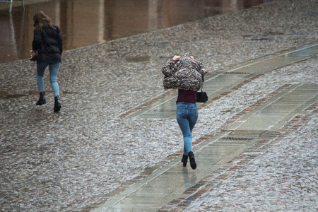 Mulhouse - France - 2 February 2020 - Portrait on back vieuw of girls running by rainy day without umbrellaのeditorial素材
