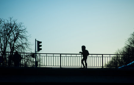 Mulhouse - France - 2 February 2020 - View of silhouette of kid walking on the bridge by sunsetのeditorial素材