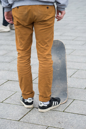 Mulhouse - France - 31 January 2020 - Closeup of skater legs wearing black sneakers by Adidas standing with skate board in the streetのeditorial素材