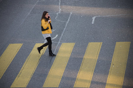 Basel - Switzerland - 7 February 2020 - Portrait on top view of woman walking on crossroad zebra with telephone in handのeditorial素材