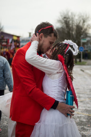 riedisheim - France - 8 February 2020 - Portrait of couple kissing in the street with orange suit and angel costume with red corns and red wingsのeditorial素材