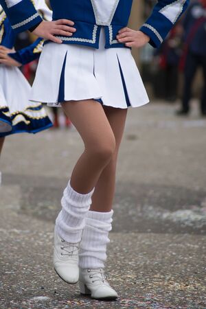 Closeup of legs of girls with sexy costume of cheerleader parading in the street
