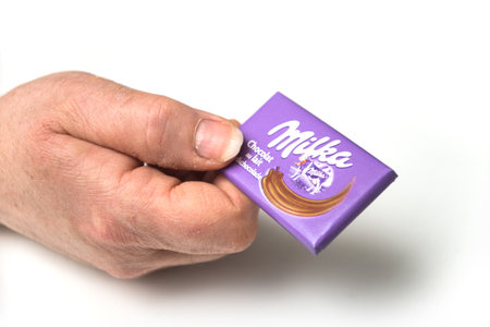 Mulhouse - France - 17 April 2020 - Closeup of mini chocolate bar by milka compagny in hand on white...