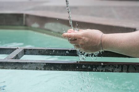 Closeup of hands of woman in the water of fountain