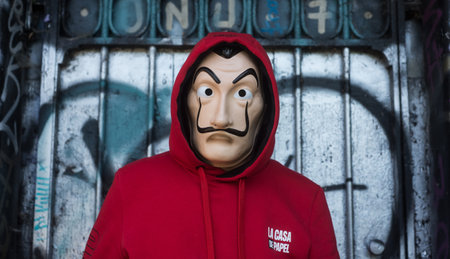 Mulhouse - France - 18 May 2020 - fan of "La casa de papel" (paper house) in english the serie TV on Netflix, standing with red sweat shirt costume and Salvador Dali mask on graffiti backgroundのeditorial素材