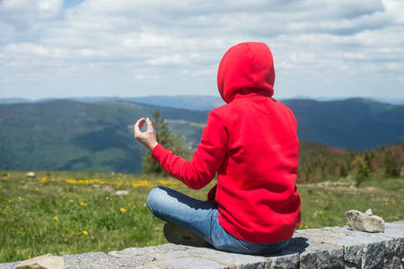 Portrait on back view of man sitting on stoned wall mediting and looking the mountain landscape