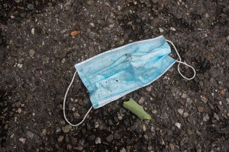 Closeup of used medical mask abandoned in the street の写真素材
