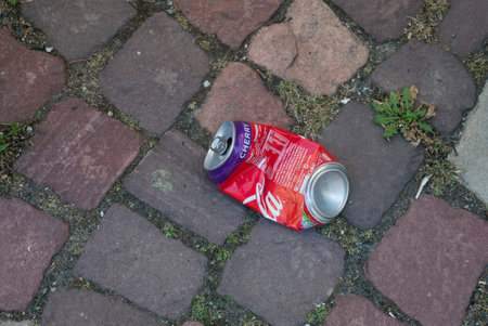 Mulhouse - France - 4 July 2020 - Closeup of abandoned crushed Coca-cola can on cobblestone in  the...