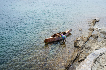 Cadaques - Spain - 10 July 2020 - portrait of african girl boarding in a wooden boat in the seaのeditorial素材