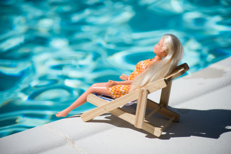 Mulhouse - France - 25 July 2020 - Portrait of Barbie doll lying in border the swimming pool in a wooden chairのeditorial素材