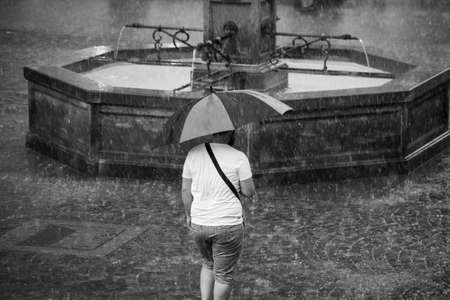 Portrait on back view of man walking in the street with an umbrella on the main place