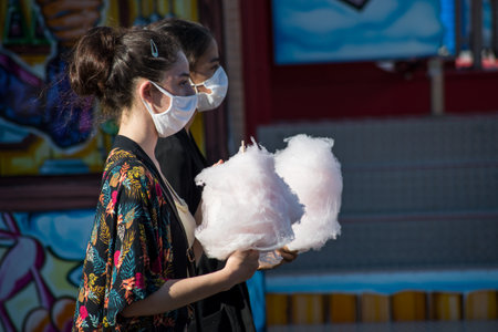 Mulhouse - France - 5 August 2020 - portrait of two young women wearing a medical mask with  cotton candy in handsのeditorial素材