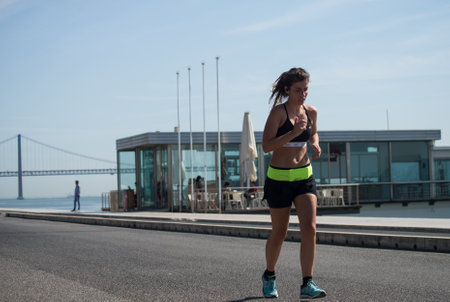 Lisbon - Portugal - 29 September 2020 - Portrait of woman running in border water on suspension bridge backgroundのeditorial素材