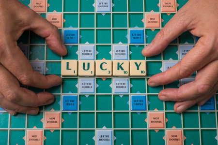 Mulhouse - France - 20 Novembre 2020 - Closeup of hands of man forming the word Lucky with scrabble letters  on the game boardのeditorial素材
