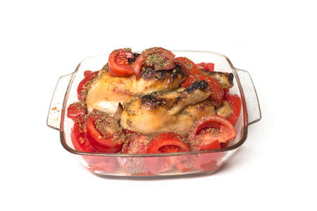 Closeup of roasted chicken with fresh tomatoes in a transparent plate on white background