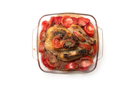 Closeup of roasted chicken with fresh tomatoes in a transparent plate on white background
