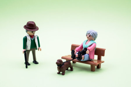 Mulhouse - France - 9 December 2020 - Closeup of playmobil character on green background - old man standing with stick andwoman sitting on bench with her dogのeditorial素材