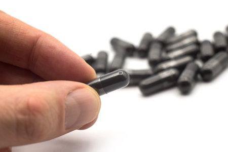 Closeup of black capsules of coal in hand on white backgroundの写真素材