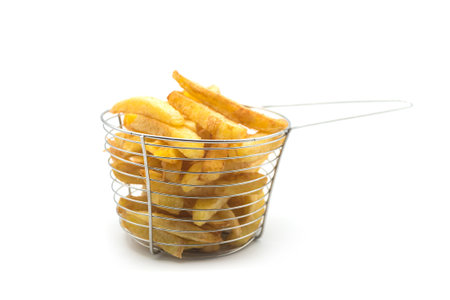 Closeup of french fries in a small metallic basket on white background