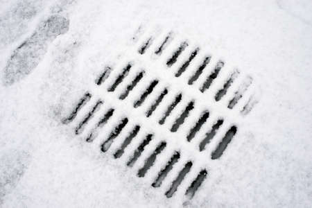 Closeup of metallic grid of drainage covered by the snow in the streetの写真素材