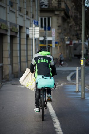 Strasbourg - France - 4 February 2021 - Portrait on back view of Uber eats delivery man with backpack on a bicycle in the streetのeditorial素材