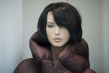Portrait of mannequin with black hairs and a winter coat in a fashion store showroomの写真素材