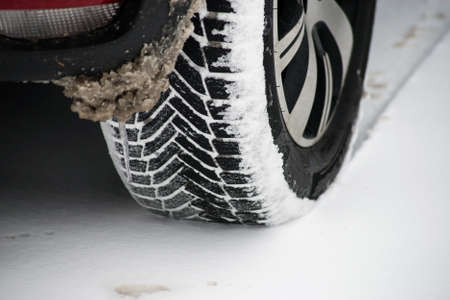 Closeup of snow tire of a parked car on a snowy day