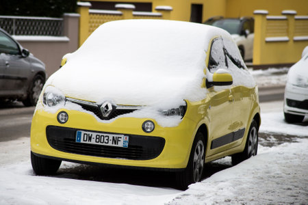 Mulhouse - France - 11 February 2021 - Front view of yellow Renault Twingo covered by the snow parkec in the streetのeditorial素材