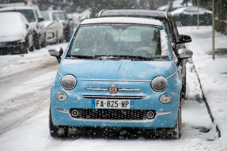 Mulhouse - France - 11 February 2021 - Front view of blue Fiat 500 parked in the street by snowy day