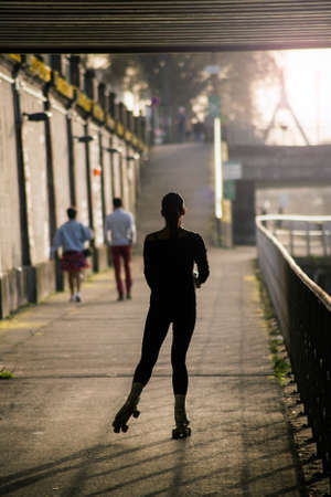 Silhouette of young woman with roller skates in border river by sunsetの写真素材