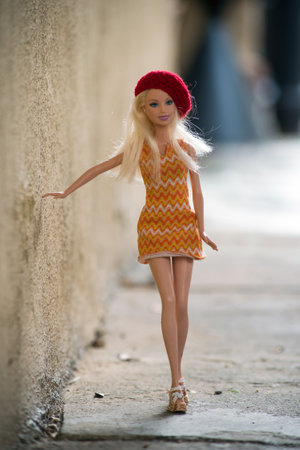 Colmar - France - 14 March 2021 - Portrait of blond Barbie doll wearing orange summer dress and red woolen beret walking in the streetのeditorial素材