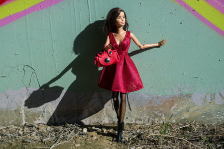 Mulhouse - France - 23 March 2021 - Portrait of Barbie doll wearing a res sexy summer dress, sexy tights and a red mini leather hand bag standing in the streetのeditorial素材