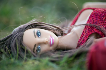 Mulhouse - France - 26 March 2021 - Portrait of brunette barbie doll wearing a red dress lying in the grassのeditorial素材