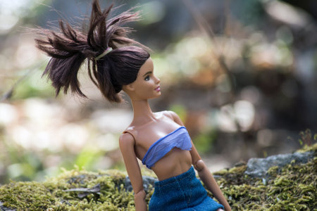 Mulhouse - France - 2 April 2021 - Portrait of Brunette Barbie doll wearing a blue jean's skirt and bikini sitting in the forestのeditorial素材