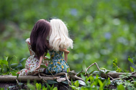 Portrait on back view of blond and brunette mannequin dolls wearing summer dresses sitting in the forestの写真素材