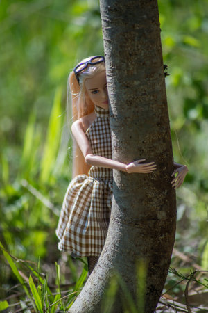Mulhouse - France - 3 May 2021 - Portrait of blond Barbie doll wearing a summer dress hugging tree in a public gardenのeditorial素材