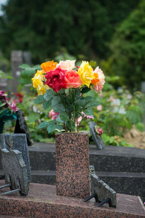 closeup of colorful artificial flowers on tomb in cemetery